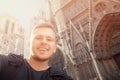 Happy male tourist takes selfie photo with Notre Dame de Paris France, backpack shoulders. Travel lifestyle concept