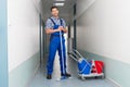 Happy male worker with broom cleaning office corridor Royalty Free Stock Photo