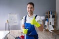 Happy Male Worker With Broom Cleaning Office