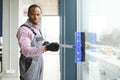 Happy Male Worker Cleaning Glass With Squeegee And Spray Bottle Royalty Free Stock Photo