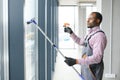 Happy Male Worker Cleaning Glass With Squeegee And Spray Bottle Royalty Free Stock Photo