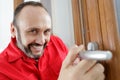 Happy male worker repairing doorknob
