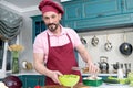 Happy man adds oil into fresh salad. Bearded smiled chef adding olive oil into vegetable salad.