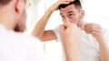 Happy man applying hair styler at bathroom