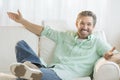 Happy Man With Arms Outstretched On Sofa