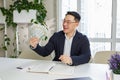 Happy man Asian businessman sitting in office holding cash money in hands and smile