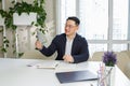 Happy man Asian businessman sitting in office holding cash money in hands and smiling