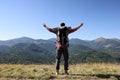 Happy man with backpack and camping mat in mountains on sunny day, back view Royalty Free Stock Photo