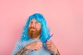 Happy man with beard and blue peruke combs her hair like a woman
