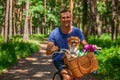 Happy man on bike with his dog in basket and tulips in the park. Royalty Free Stock Photo