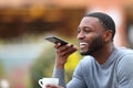 Happy man with black skin dictating message on phone