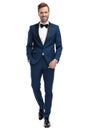 Happy man in blue tuxedo walking with hand in pocket