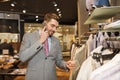 Happy man calling on smartphone at clothing store Royalty Free Stock Photo