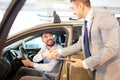 Happy man with car dealer in auto show or salon Royalty Free Stock Photo