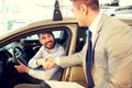 Happy man with car dealer in auto show or salon Royalty Free Stock Photo