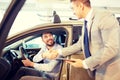 Happy man with car dealer in auto show or salon Royalty Free Stock Photo