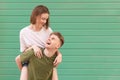 Happy man carries his girlfriend on his back, looking at her and smiling. Portrait of a young lovers couple against the backdrop Royalty Free Stock Photo