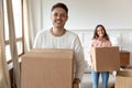 Happy man carrying box moving into new house with girlfriend