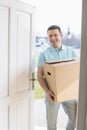 Happy man carrying cardboard box while entering new house Royalty Free Stock Photo