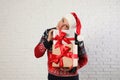 Happy man in Christmas sweater and Santa hat holding gift boxes Royalty Free Stock Photo