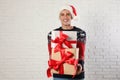 Happy man in Christmas sweater and Santa hat holding gift boxes Royalty Free Stock Photo