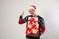 Happy man in Christmas sweater and Santa hat holding gift boxes near white brick Royalty Free Stock Photo