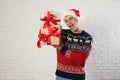 Happy man in Christmas sweater and Santa hat holding gift boxes Royalty Free Stock Photo