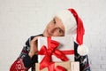 Happy man in Christmas sweater and Santa hat holding gift boxes near white brick Royalty Free Stock Photo