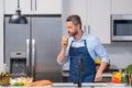 Happy man in cook apron cooking with bottle olive oil in kitchen. Portrait of middle aged man in chef apron in kitchen Royalty Free Stock Photo