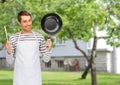 Happy man or cook in apron with pan and spoon Royalty Free Stock Photo