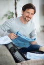 happy man on couch preparing travel back and packing suitcase Royalty Free Stock Photo