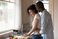 Happy man cuddling cheerful black woman preparing food. Royalty Free Stock Photo