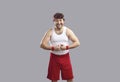 Happy man in tank top and shorts smiling and flexing his arms showing his muscles Royalty Free Stock Photo