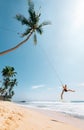 Happy man dangles on tropical palm tree swing Royalty Free Stock Photo