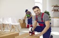 Happy man from delivery service or moving company sealing box using tape dispenser Royalty Free Stock Photo