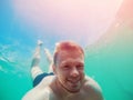 Happy man dives under sea with action camera, takes selfie photo. Concept snorkeling