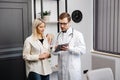 Happy man doctor showing tablet woman patient in clinic office interior. Health care, visit to family therapist, treatment of Royalty Free Stock Photo