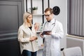 Happy man doctor showing tablet woman patient in clinic office interior. Health care, visit to family therapist, treatment of Royalty Free Stock Photo