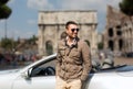 Happy man driving cabriolet car over city of rome Royalty Free Stock Photo