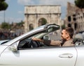 Happy man driving cabriolet car over city of rome Royalty Free Stock Photo