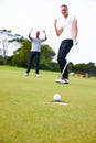 Happy man, friends and golfer with winner for goal in hole on the green grass or outdoor field in nature. Male person or Royalty Free Stock Photo