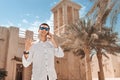 Man gestures and smiles while talking on the phone against the backdrop of a wind tower in the old Bur Dubai Creek Royalty Free Stock Photo