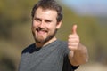 Happy man gesturing thumbs up at camera in nature Royalty Free Stock Photo