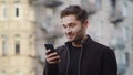 Happy man getting great news phone outside. Overjoyed guy using phone outdoors Royalty Free Stock Photo