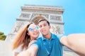 Man and a girl hug and take a selfie photo against the Arc de Triomphe in Paris. Honeymoon and a trip together in France