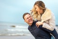 Happy man giving piggyback ride to his woman and laughing at beach. Smiling guy in love carrying on back her girlfriend Royalty Free Stock Photo