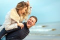 Happy man giving piggyback ride to his woman and laughing at beach. Smiling guy in love carrying on back her girlfriend Royalty Free Stock Photo