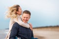 Happy man giving piggyback ride to his woman and laughing at beach. Smiling guy in love carrying on back her girlfriend Royalty Free Stock Photo