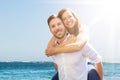 Happy Man Giving Piggyback To His Wife At Beach