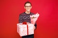 Happy man in glasses, man with a gift and a bouquet of flowers in his hands, on a red background Royalty Free Stock Photo